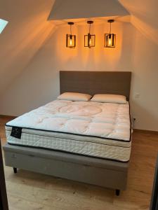 Una cama en una habitación con dos luces encima. en Maison avec Jardin à 5 minutes du grand stade PIERRE MAUROY en Lezennes
