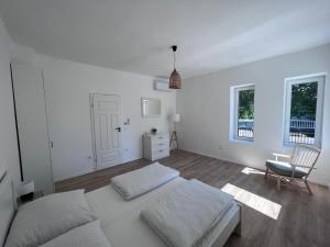 a white bedroom with a bed and a chair at Best Apartman Boglár in Balatonboglár