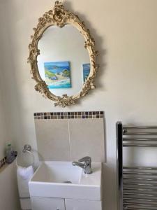 baño con lavabo y espejo en la pared en Light airy comfy small double room with en-suite, en Falmouth