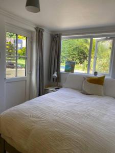 1 dormitorio con 1 cama grande y 2 ventanas en Light airy comfy small double room with en-suite, en Falmouth