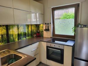 a kitchen with a sink and a refrigerator and a window at Alpenblick mit super Bergblick und Terrasse in Oberammergau