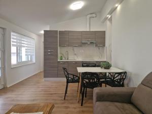 a living room with a table and chairs and a kitchen at Apartman Anka in Komin