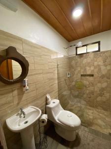 uma casa de banho com um lavatório, um WC e um espelho. em Gambas Lodge em La Fortuna