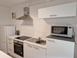 eine weiße Küche mit Mikrowelle und Spüle in der Unterkunft Sson Rentals in Detmold