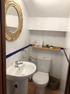 uma casa de banho com um WC, um lavatório e um espelho. em ALOJAMIENTO RURAL EL CASTAÑO em Fuenteheridos