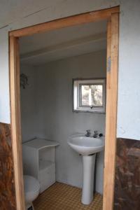 a bathroom with a sink and a toilet and a window at Refugio El Cauque in Puerto Williams