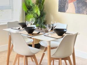 - une table à manger avec des chaises blanches et des bols noirs dans l'établissement Lyter Living-The Foundry-Jericho-Oxford-Parking Included, à Oxford