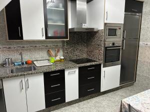 a kitchen with black and white cabinets and appliances at Vista puerto deportivo in Villanueva de Arosa