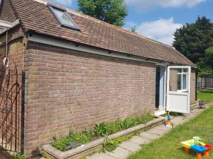 a brick house with a white door and a yard at Cosy Studio Luton in Luton