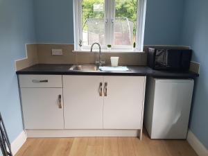 a kitchen counter with a sink and a microwave at Cosy Studio Luton in Luton