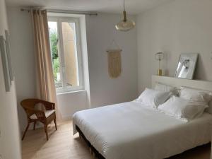 a bedroom with a white bed and a chair and a window at La Petite Maison in Châteauroux