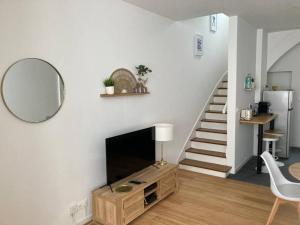 a living room with a television and a staircase at La Petite Maison in Châteauroux