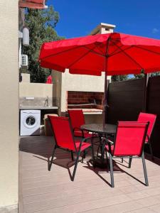 - une table et des chaises avec un parasol rouge sur la terrasse dans l'établissement Casa para 4 personas en vista24uy, Bella Vista, Maldonado, à Bella Vista