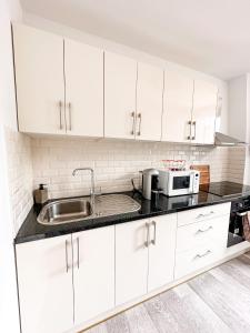 a kitchen with white cabinets and a sink at Logement entier 75 m2 in Boulogne-Billancourt