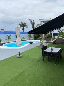 un patio con tavolo e sedie accanto alla piscina di Tagoro Sunset View & Heated Pool Tenerife a Santa Cruz de Tenerife