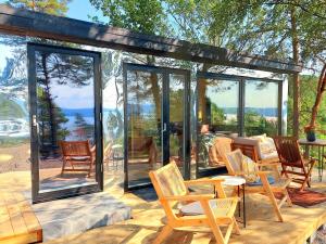 een glazen serre met stoelen en tafels op een houten terras bij fjord : oslo 