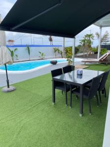 a table and chairs under a black umbrella next to a pool at Tagoro Sunset View & Heated Pool Tenerife in Santa Cruz de Tenerife