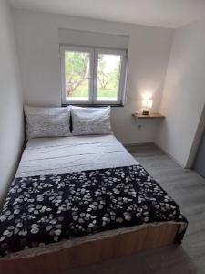 a small bedroom with a bed with a window at Apartman Marija in Zlarin