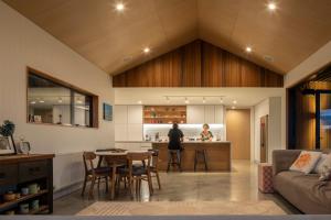 a living room and kitchen with a person in the kitchen at Twin Peaks Beach House - New Plymouth Holiday Home in New Plymouth