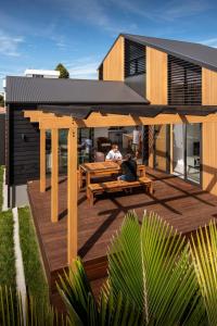 two people sitting on the deck of a house at Twin Peaks Beach House - New Plymouth Holiday Home in New Plymouth