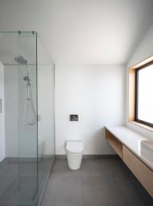 a bathroom with a toilet and a glass shower at Twin Peaks Beach House - New Plymouth Holiday Home in New Plymouth