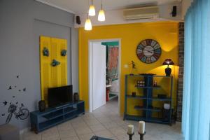 a living room with a yellow wall and a tv at Lux δυάρι με parking στο κέντρο in Volos