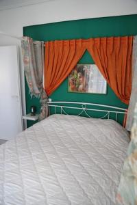 - une chambre avec un lit blanc et un rideau orange dans l'établissement Lux δυάρι με parking στο κέντρο, à Vólos
