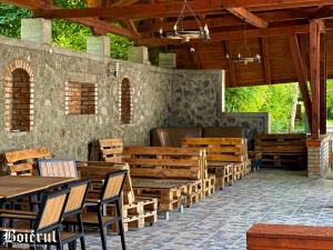 eine Terrasse mit Holztischen und -stühlen in einem Gebäude in der Unterkunft Boierul la Florenta in Dej