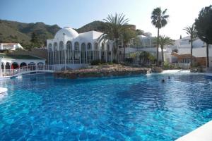 a swimming pool with blue water in a resort at Capistrano1 in Nerja
