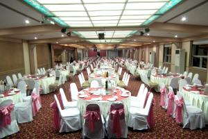 a large banquet hall with white tables and chairs at Tanyong Hotel in Narathiwat