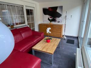 ein Wohnzimmer mit einem roten Sofa und einem Tisch in der Unterkunft Stilvolles Ferienhaus mit Garten für 6 Personen in Dippoldiswalde