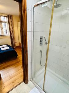 La salle de bains est pourvue d'une douche avec une porte en verre. dans l'établissement London Mackenzie Apartment, à Londres
