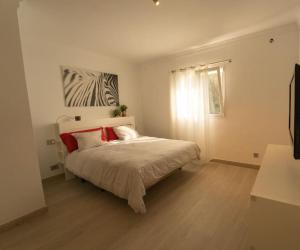 a bedroom with a bed with red pillows and a window at Finca Artiles in Las Palmas de Gran Canaria