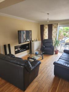 a living room with black leather furniture and a flat screen tv at Cosy 3 Bedroom Home in Notts in Nottingham