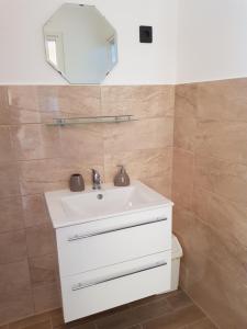 a bathroom with a white sink and a mirror at Henrietta Apartmanház in Zalakaros