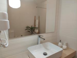 a white bathroom with a sink and a mirror at Estúdio Lagoa Azul in Vila Nova de Milfontes