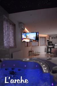 eine große blaue Badewanne in einem Zimmer mit einem Flachbild-TV in der Unterkunft L'Arche Loft nid douillet - Spa privatif in Grenoble