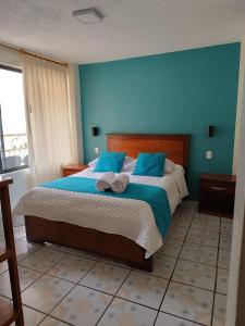 a bedroom with a large bed with blue walls at Hostal CañaLimeña in Baños