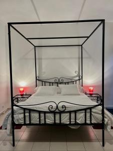 a bedroom with a black canopy bed with two red candles at The coolest room in Rufisque