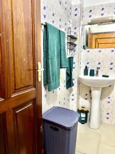 baño con toallas verdes, lavabo y cubo de basura en The coolest room, en Rufisque