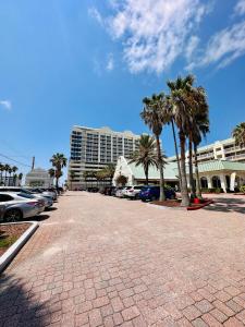 a parking lot with palm trees and a large building at Daytona Beach Resort Oceanfront CondoStudio in Daytona Beach