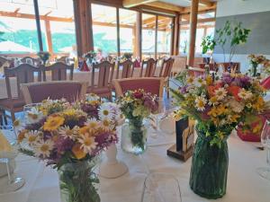 una mesa con jarrones llenos de flores. en Berggasthof Karlbauer, en Lendorf