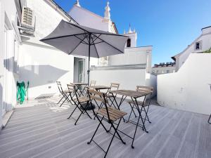 een terras met een tafel, stoelen en een parasol bij Guest House DML in Aveiro
