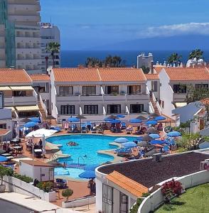a resort with a swimming pool with chairs and umbrellas at Apartamento Helena en Garden City con piscina climatizada in Playa Fañabe