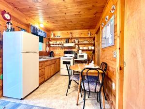 eine Küche mit einem Tisch und einem Kühlschrank in der Unterkunft Stargazers Cove Cottages Otter in Middleton