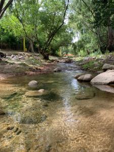 un arroyo con rocas en un río con árboles en Cabañas las Calandrias en Potrero de los Funes