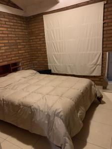 duże łóżko w pokoju z ceglaną ścianą w obiekcie Cabañas las Calandrias w mieście Potrero de los Funes