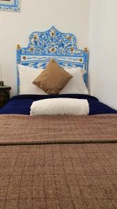 a bed with a blue and white headboard and pillows at Casa Familia in Chefchaouen