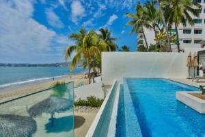 une piscine avec une plage et un bâtiment dans l'établissement Nova - Beachfront Condo with Private Office & Panoramic Views, à Bucerías