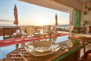 une table avec des assiettes et des verres à vin et une vue sur l'océan dans l'établissement Nova - Beachfront Condo with Private Office & Panoramic Views, à Bucerías